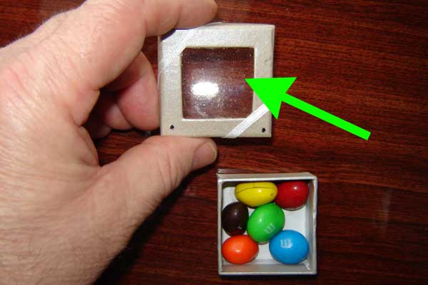 The clear film is actually a light-sensitive emulsion. This is exposed in a laser laboratory. It looks like any other clear lid to a box of candy. Below you will see what happens with a laser pointer.